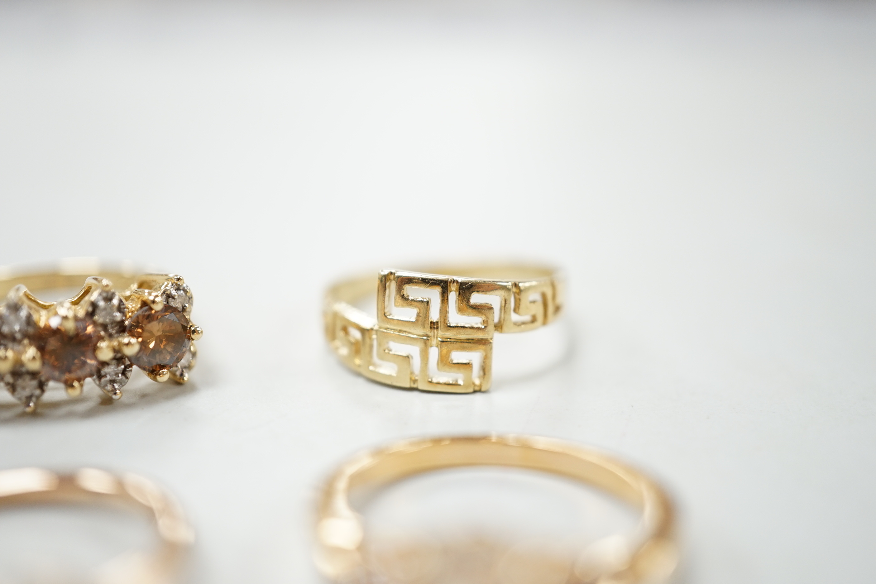 Three assorted modern 585 yellow metal and gem set rings, including two rose coloured and a 585 'Greek Key' ring, gross weight 11.1 grams.